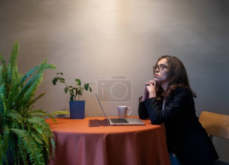 Une seule femme pigiste est assise seule sur un ordinateur portable le soir, travaillant, lisant des nouvelles ou bavardant sur les médias sociaux. Problème moderne de solitude dans la vie réelle, mais actif dans le monde numérique.