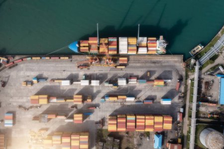 Top down aerial view of cargo ship loading containers. Showcases maritime shipping efficiency. Part of global distribution network.