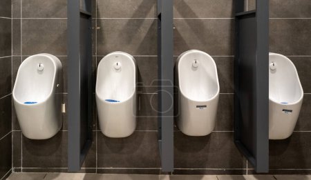 Row of modern white urinals in public restroom.