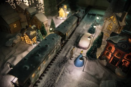 Photo for Miniature of winter scene with Christmas houses, train station, trees, covered in snow. Nights scene. New year in vintage toy city. Selective focus - Royalty Free Image