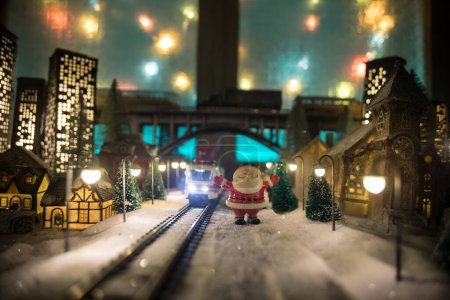Foto de Miniatura de escena invernal con casas de Navidad, estación de tren, árboles, cubiertos de nieve. Escena nocturna. Nuevo año en la ciudad de juguete vintage. Enfoque selectivo - Imagen libre de derechos
