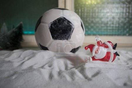 Photo for World cup at wintertime concept. Football (Soccer) ball on snowy decorated table with toy miniatures. New Year Christmas theme. Selective focus. Low light - Royalty Free Image