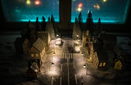 Foto de Pequeñas casas pequeñas decorativas en la nieve por la noche en invierno, Navidad y Año Nuevo casa en miniatura en la nieve por la noche con abeto. Concepto de vacaciones. Enfoque selectivo - Imagen libre de derechos