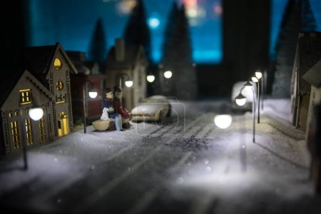 Téléchargez les photos : Petites maisons décoratives mignonnes dans la neige la nuit en hiver, Noël et Nouvel An maison miniature dans la neige la nuit avec sapin. Concept de vacances. Concentration sélective - en image libre de droit