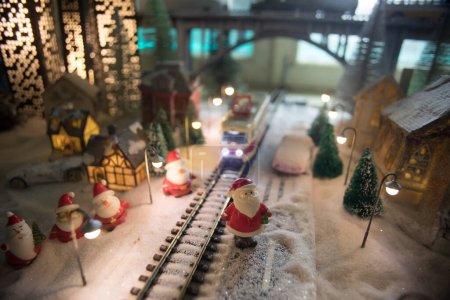 Foto de Miniatura de escena invernal con casas de Navidad, estación de tren, árboles, cubiertos de nieve. Escena nocturna. Nuevo año en la ciudad de juguete vintage. Enfoque selectivo - Imagen libre de derechos