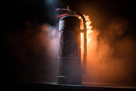 Photo for Fire protection concept. Old fire extinguisher on dark foggy background with light. Selective focus - Royalty Free Image