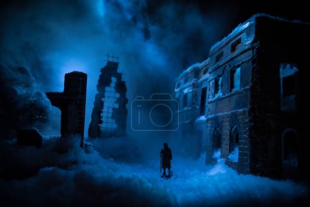 Foto de War apocalypse concept. Snow covered ruined city destroyed by war. Refugees and civilians silhouettes on dark. Creative artwork decoration in dark. Selective focus - Imagen libre de derechos