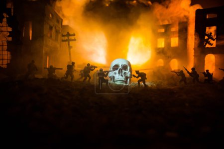 Foto de Concept of death soldiers during the war. Giant human skull with military fighting silhouettes in destroyed city. Selective focus - Imagen libre de derechos