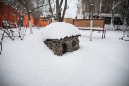 Téléchargez les photos : A little stone house covered with snow at the garden during wintertime. Decorative little house. - en image libre de droit