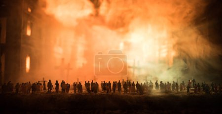 Silhouettes of a crowd standing at field behind the blurred foggy background. Selective focus. Revolution, people protest against government. Destroyed city on background
