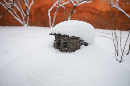 Téléchargez les photos : A little stone house covered with snow at the garden during wintertime. Decorative little house. - en image libre de droit