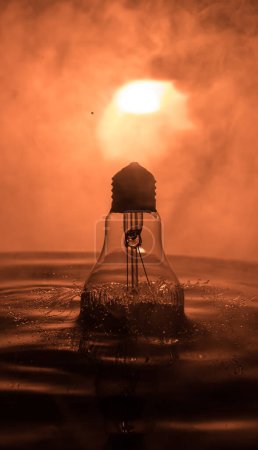 Photo for Abstract concept. Light bulb dropping on water or water splash on dark foggy background. Selective focus. - Royalty Free Image