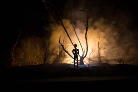 Téléchargez les photos : Silhouette de la personne debout dans la forêt sombre. Horreur concept d'Halloween. étrange silhouette dans une sombre forêt effrayante la nuit - en image libre de droit