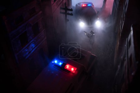 Photo for Police raid at night and you are under arrest concept. Silhouette of police car on backside. Image with the flashing red and blue police lights at foggy background. - Royalty Free Image