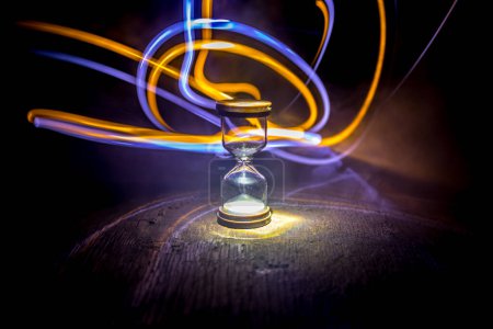 Photo for Hourglass as time passing concept for business deadline, urgency and running out of time. Sandglass, egg timer on dark background showing the last second or last minute or time out. With copy space. - Royalty Free Image