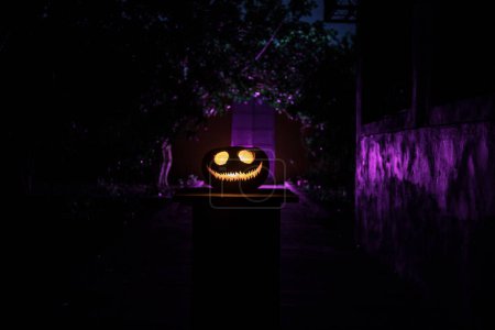 Photo for Pumpkin Burning In Forest at night. Abandoned building in forest. Scary Jack o Lantern smiling and glowing pumpkin with dark toned foggy background. Selective focus - Royalty Free Image