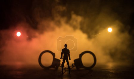 Photo for Legal law or crime and execution concept. Death penalty miniatures on table. Man alone looking to execution at night. Artwork decoration with handcuffs, Statue of Justice and mallet of justice - Royalty Free Image