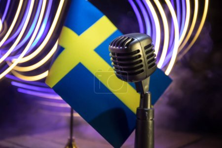 Micrófono en un fondo de una bandera borrosa Suecia primer plano. decoración de mesa oscura. Enfoque selectivo