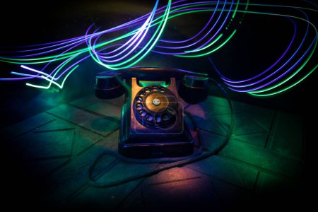 Photo for Old black telephone on old wood plank with art dark background with fog and toned light. empty space. Selective focus - Royalty Free Image