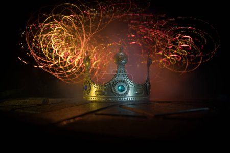 Photo for Low key image of beautiful kings crown over wooden table. vintage filtered. fantasy medieval period. Selective focus. Colorful backlight - Royalty Free Image