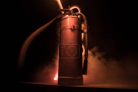 Foto de Concepto de protección contra incendios. Antiguo extintor de incendios sobre fondo oscuro brumoso con luz. Enfoque selectivo - Imagen libre de derechos