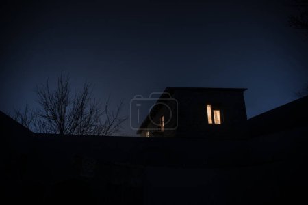 Photo for Old house with a Ghost in the forest at night or Abandoned Haunted Horror House in fog. Old mystic building in dead tree forest. Trees at night with moon. Surreal lights. Horror Halloween concept - Royalty Free Image