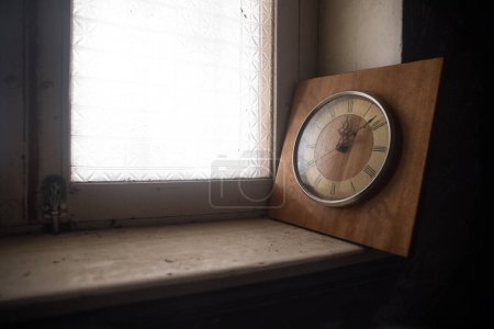Foto de Time concept. Old rustic wall clock on grunge dirty windowsill. Studio shot. - Imagen libre de derechos