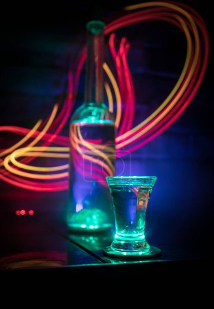 Téléchargez les photos : Verre de vodka froide sur fond sombre dans la lumière au néon ou verres de vodka russe sur fond de bar. focus sélectif - en image libre de droit