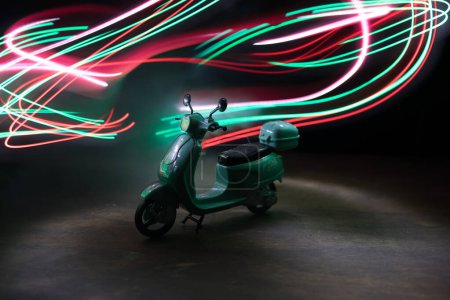 Téléchargez les photos : Silhouette de scooter miniature debout sur fond sombre avec de la lumière. Concentration sélective - en image libre de droit