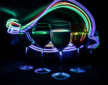 Photo for Wine glass on dark bar background low light. Colorful wine glasses with light on backside in selective focus - Royalty Free Image