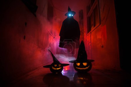 Téléchargez les photos : Concept d'Halloween. Silhouette effrayante dans le couloir sombre avec tête de citrouille. Lumière tonique avec brouillard sur le fond. Concentration sélective. Long coup d'obturateur - en image libre de droit