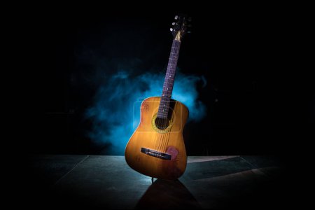 Photo for Music concept. Acoustic guitar isolated on a dark background under beam of light with smoke with copy space. Guitar Strings, close up. Selective focus. - Royalty Free Image