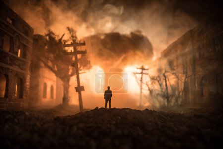 Photo for Artwork decoration. A man standing on a road of burnt up city. Apocalyptic view of city downtown as disaster film poster concept. Night scene. City destroyed by war. Selective focus - Royalty Free Image