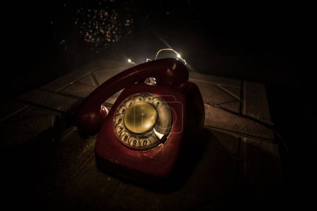 Photo for Old red telephone on grunge stone surface with art dark background with fog and toned light. empty space. Selective focus - Royalty Free Image