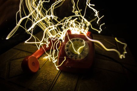 Téléchargez les photos : Vieux téléphone rouge sur la surface de pierre grunge avec fond sombre art avec brouillard et lumière tonique. espace vide. Concentration sélective - en image libre de droit