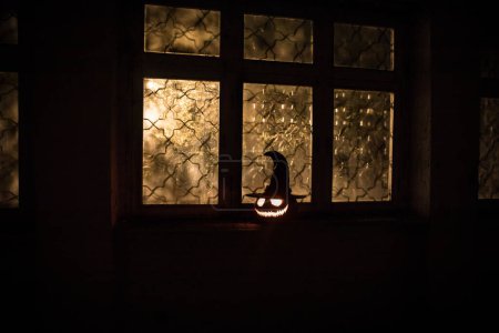 Téléchargez les photos : Citrouille d'Halloween effrayant dans la fenêtre de la maison mystique la nuit ou citrouille d'Halloween la nuit sur la chambre abandonnée avec fenêtre. Concentration sélective - en image libre de droit