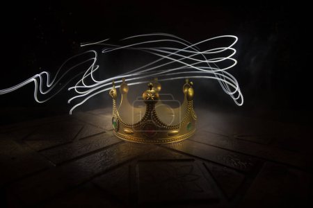 Photo for Low key image of beautiful kings crown over wooden table. vintage filtered. fantasy medieval period. Selective focus. Colorful backlight - Royalty Free Image