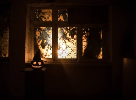 Foto de Calabaza de Halloween miedo en la ventana de la casa mística por la noche o la calabaza de Halloween y silueta de horror en la ventana. Enfoque selectivo - Imagen libre de derechos