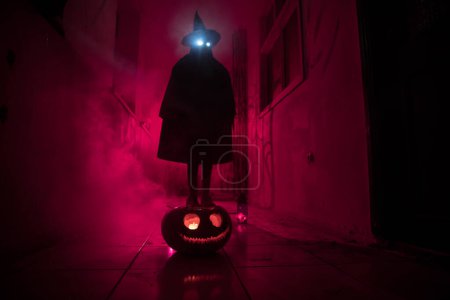 Photo for Halloween concept. Creepy silhouette in the dark corridor with pumpkin head. Toned light with fog on background. Selective focus. Long shutter shot - Royalty Free Image