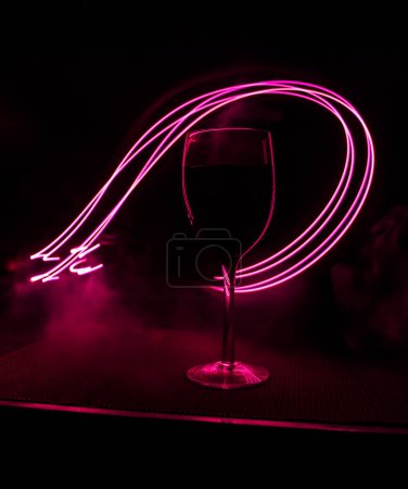 Téléchargez les photos : Verre à vin sur fond de barre sombre faible luminosité. Verres à vin colorés avec lumière au dos en mise au point sélective - en image libre de droit