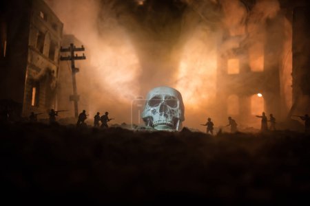 Téléchargez les photos : Concept of death soldiers during the war. Giant human skull with military fighting silhouettes in destroyed city. Selective focus - en image libre de droit