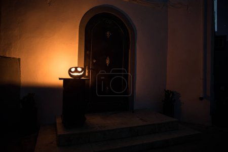Foto de Puerta de entrada a una casa decorada con calabaza de Halloween. Calabaza de Halloween en una puerta empinada por la noche. Enfoque selectivo - Imagen libre de derechos