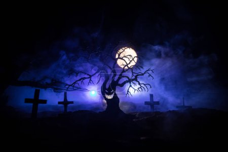 Photo for Silhouette of scary Halloween tree on dark foggy toned background with moon on back side. Scary horror winter dead forest at night. selective focus - Royalty Free Image