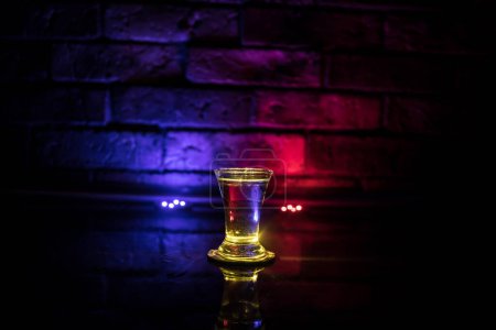 Foto de Vidrio de vodka frío sobre un fondo oscuro en la luz de neón o vasos de vodka ruso sobre el fondo de la barra. enfoque selectivo - Imagen libre de derechos