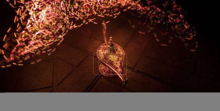 Téléchargez les photos : Antique Aladdin arabian nuits lampe à huile de style génie avec fumée blanche douce lumière, fond foncé. Concept Lampe de voeux - en image libre de droit