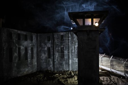Photo for Criminal justice imprisonment concept. Old prison watchtower protected by wire of prison fence at night. Creative art decoration. Selective focus - Royalty Free Image