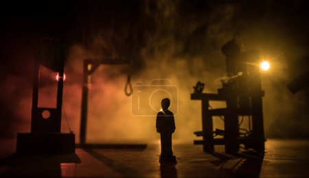 Photo for Legal law or crime and execution concept. Death penalty miniatures on table. Man alone looking to execution at night. Artwork decoration with handcuffs, Statue of Justice and mallet of justice - Royalty Free Image