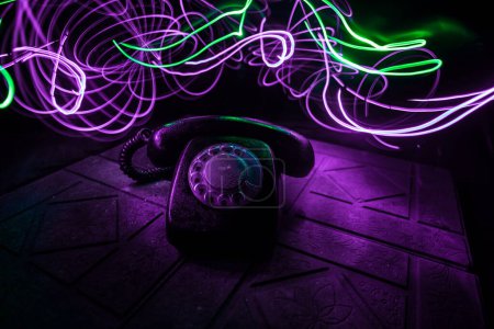 Photo for Old red telephone on grunge stone surface with art dark background with fog and toned light. empty space. Selective focus - Royalty Free Image