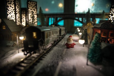 Photo for Miniature of winter scene with Christmas houses, train station, trees, covered in snow. Nights scene. New year in vintage toy city. Selective focus - Royalty Free Image