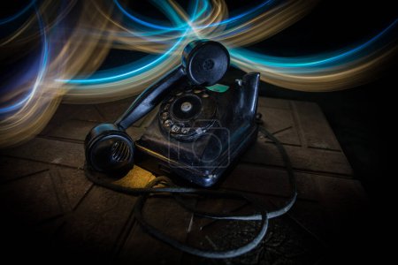 Foto de Viejo teléfono negro sobre tabla de madera vieja con arte fondo oscuro con niebla y luz tonificada. espacio vacío. Enfoque selectivo - Imagen libre de derechos